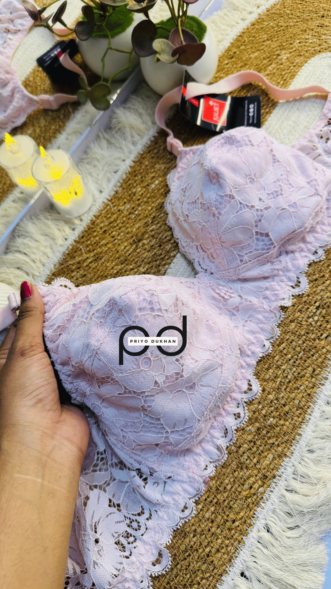 White lace bra with 'pd' branding held by a hand on a patterned surface.